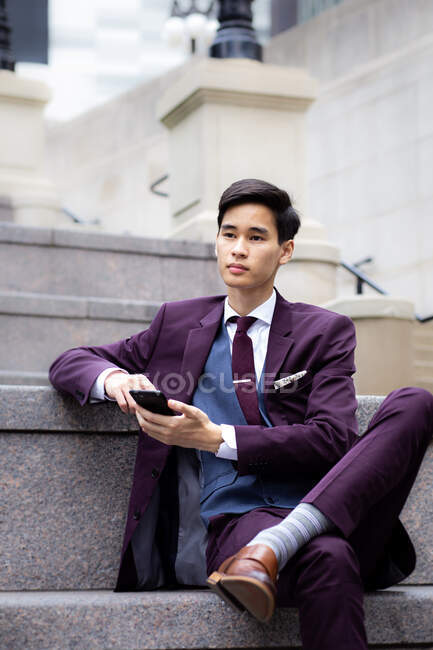 Young Businessman sitting on riverwalk using his mobile phone, Chicago, Illinois, USA — Stock Photo