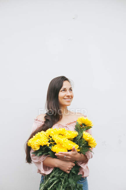 Donna sorridente che tiene un mazzo di crisantemi gialli — Foto stock