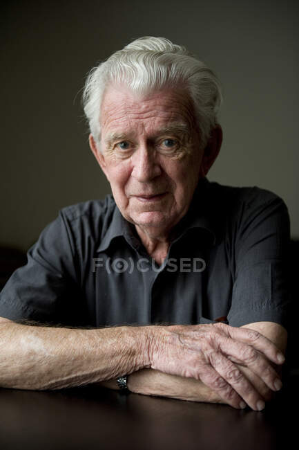 Porträt eines älteren Mannes, der an einem Tisch sitzt — Stockfoto