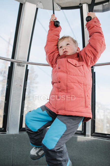 Boy in an overhead cable car holding onto handles, Mammoth Lakes, California, USA — Stock Photo