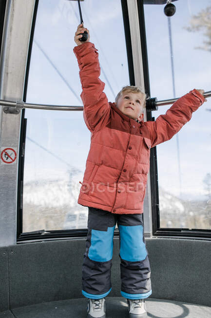 Junge in einer Schwebebahn, die sich an einem Geländer festhält, Mammoth Lakes, Kalifornien, USA — Stockfoto