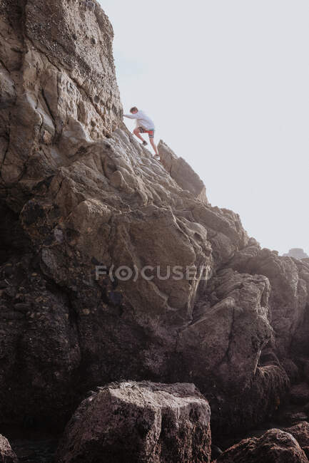 Garçon escalade rochers sur chaque, Dana Point, Californie, États-Unis — Photo de stock