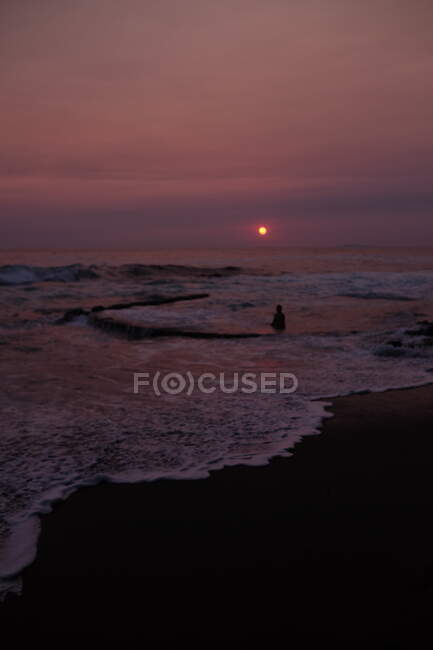 Frau sitzt bei Sonnenuntergang in einem Gezeitenpool, Laguna Beach, Kalifornien, USA — Stockfoto