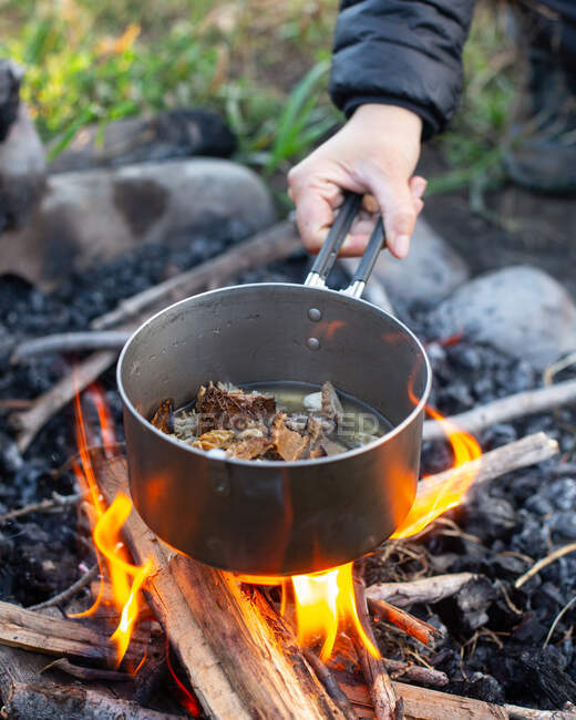 Mujer cocinando sobre un fuego abierto, EE.UU. - foto de stock