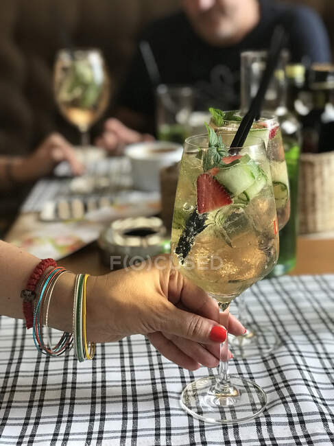 Жінка сидить за столом тримає коктейльний келих — стокове фото