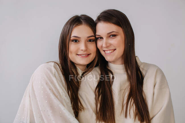 Портрет двух улыбающихся сестер на белом фоне — стоковое фото