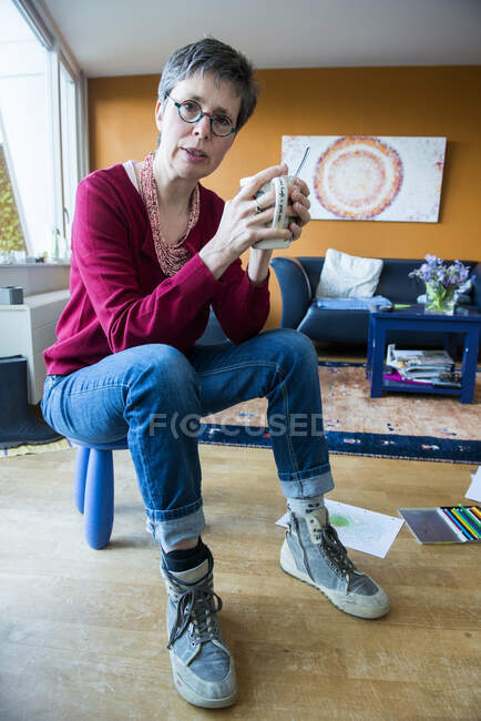 Frau sitzt mit Heißgetränk auf einem Hocker — Stockfoto