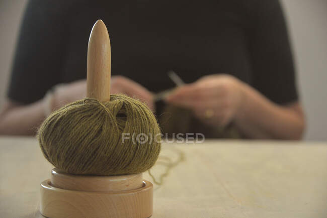 Dérouleur de laine sur une table devant une femme tricot — Photo de stock