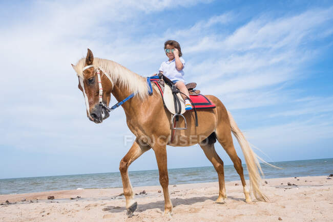 Garçon chevauchant un cheval sur la plage, Thaïlande — Photo de stock