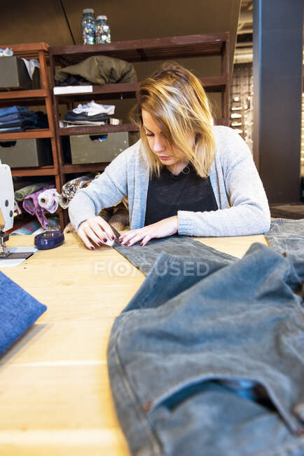 Seamstress adjusting a pair of jeans in her studio — Foto stock