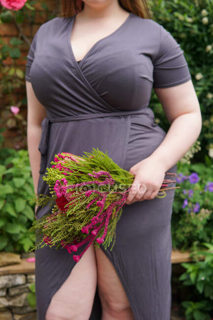 Femme debout dans un jardin tenant un bouquet de fleurs, Angleterre, Royaume-Uni — Photo de stock