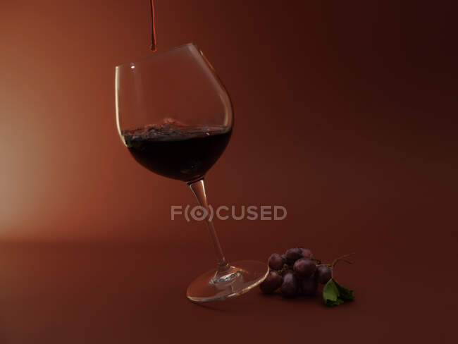 Un verre de vin rouge et un bouquet de raisins rouges — Photo de stock