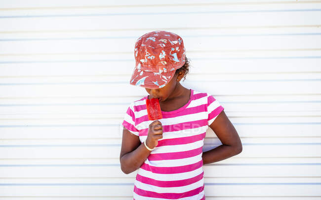 Retrato de una chica comiendo un caramelo de hielo - foto de stock