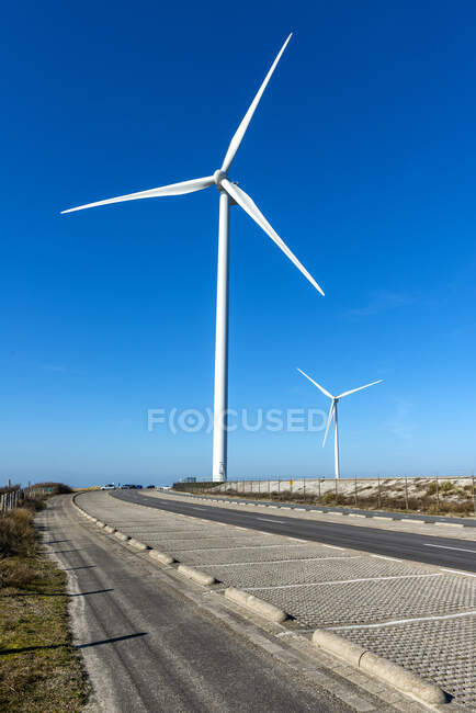 Moinho de vento na estrada em luz solar brilhante com céu azul — Fotografia de Stock