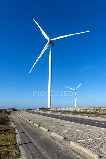 Molino de viento en la carretera en la luz del sol brillante con el cielo azul - foto de stock