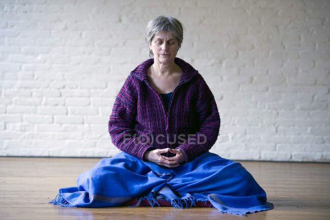 Портрет старшої жінки, що сидить на схрещених ногах медитує — стокове фото