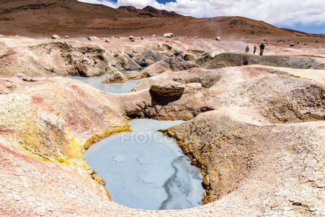 Three people walking past geysers, Altiplano, Bolivia — Stock Photo