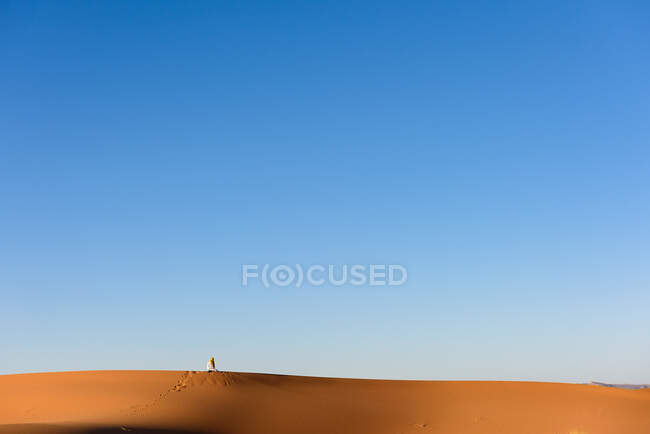 Distant view of a Berber man praying in the Sahara desert, Morocco — Stock Photo