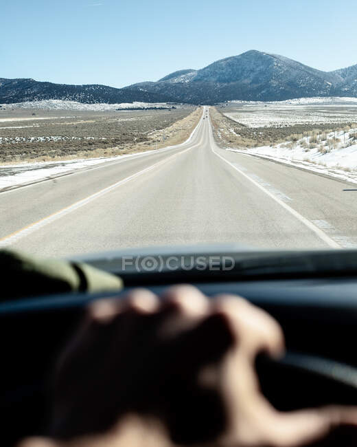 Car driving along an empty road towards mountains, Utah, United States — Stock Photo