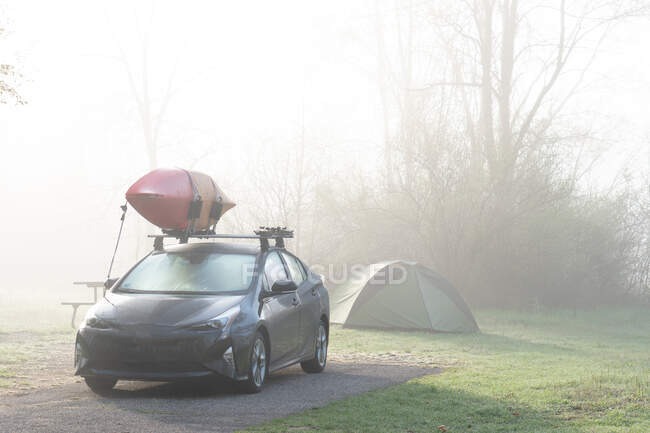 Car with a canoe parked by a tent in the woods, Fort Custer State Recreational Area, Indiana, United States — Stock Photo
