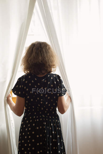 Teenage girl looking through a window — Stock Photo