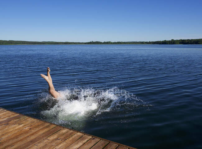 Mujer sumergiéndose en el mar desde un embarcadero de madera, Lituania - foto de stock