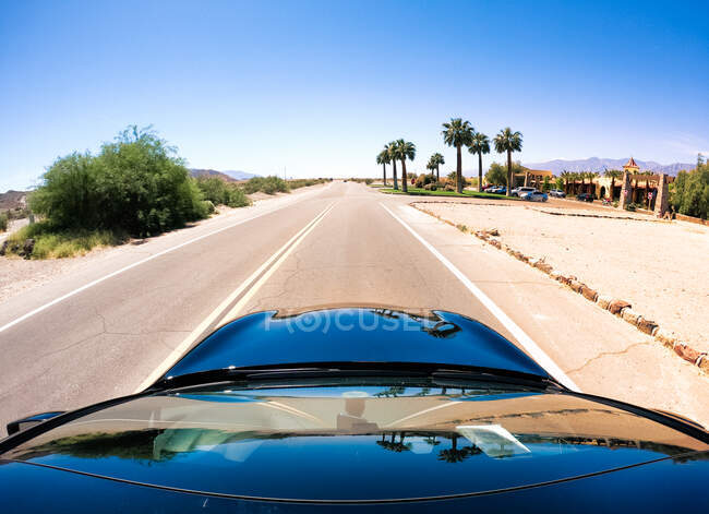Coche acercándose a un oasis a lo largo de una carretera desierta, Nevada, Estados Unidos - foto de stock