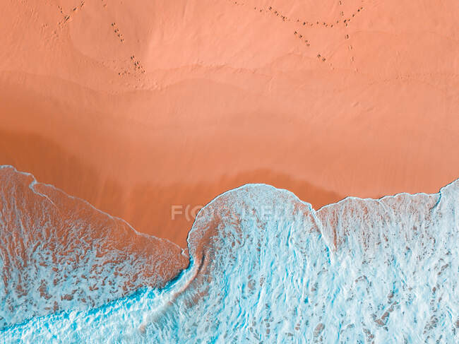 Vista aerea della costa sabbiosa vicino al mare ondulato nella giornata di sole — Foto stock
