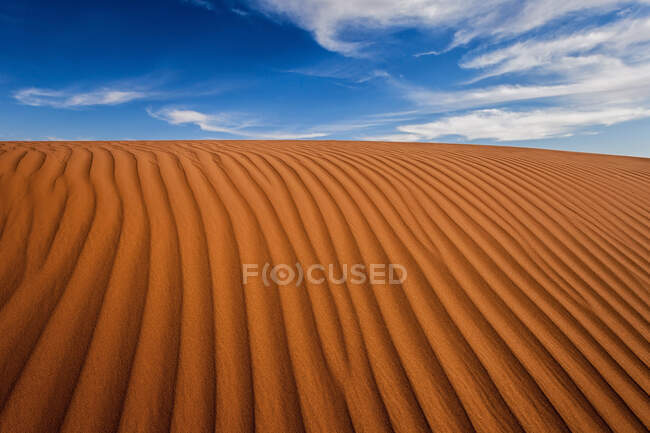 Dune désertique rayée sous un ciel nuageux bleu, Arabie Saoudite — Photo de stock