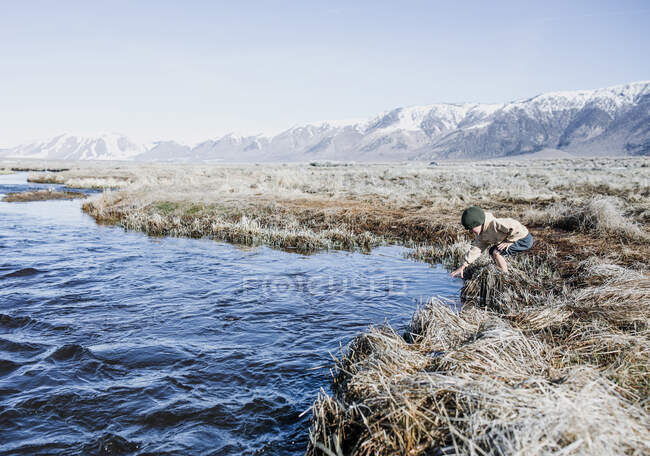 Boy standing by a river, Mammoth Lakes, California, Estados Unidos - foto de stock