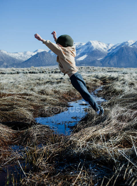 Boy jumping over a stream, Mammoth Lakes, Califórnia, Estados Unidos — Fotografia de Stock