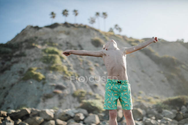 Мальчик стоит на пляже с протянутыми руками Лагуна-Бич, Калифорния, США — стоковое фото