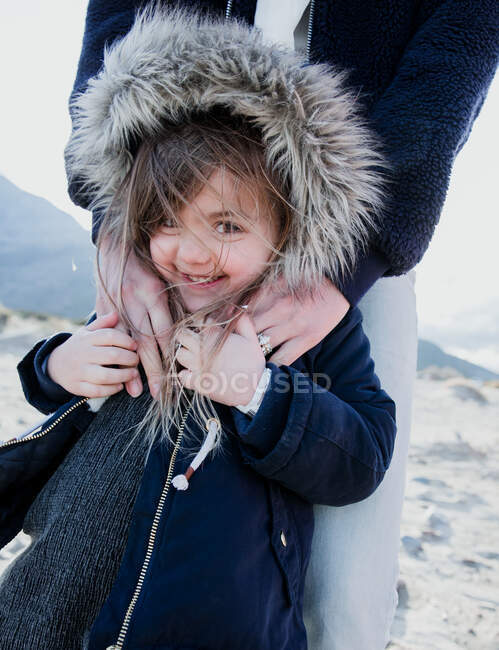 Портрет матери, обнимающей свою дочь в фальшивой меховой куртке в капюшоне, Палм-Спрингс, Калифорния, США — стоковое фото
