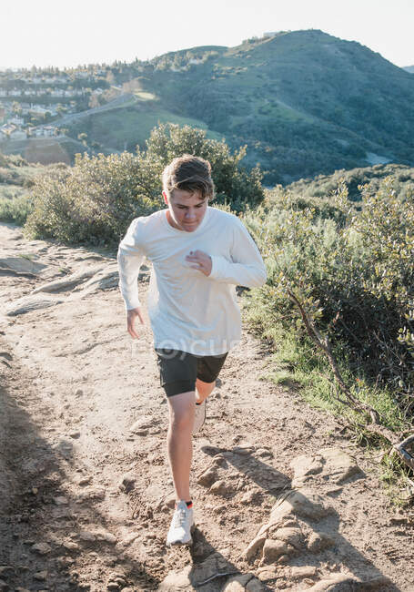 Мальчик-подросток бежит по пустынной тропе, Палм-Спрингс, Калифорния, США — стоковое фото
