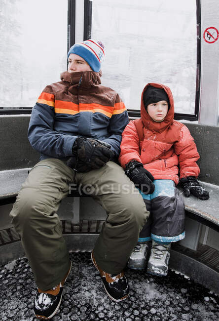 Two boys sitting in a gondola going snowboarding, California, United States — Stock Photo