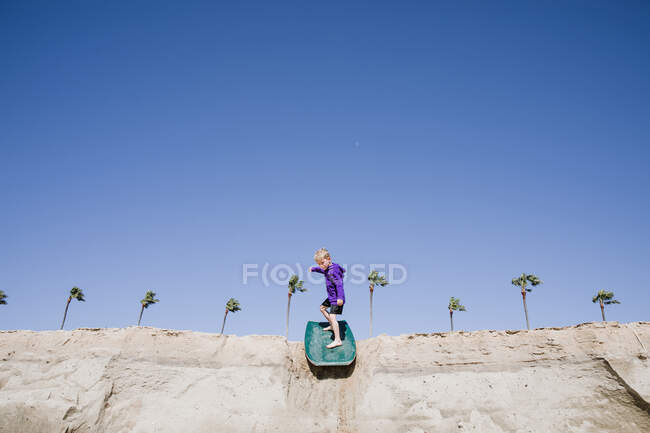 Boy sandboarding en la playa, Laguna Beach, California, Estados Unidos - foto de stock