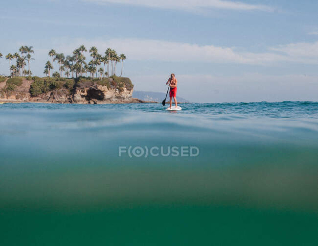 Teenage boy standing on a surfboard paddling, Laguna Beach, California, United States — Stock Photo