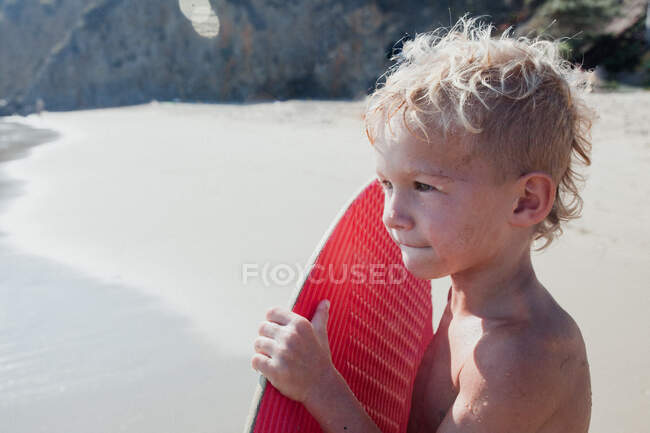Portrait d'un garçon sur la plage portant un skimboard, Laguna Beach, Californie, États-Unis — Photo de stock