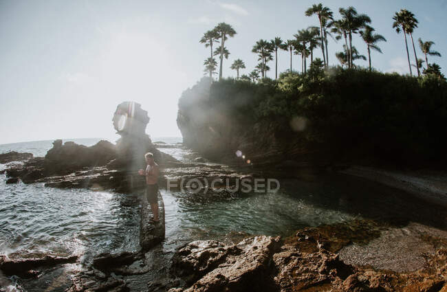 Man standing on rocks by a tide pool, Laguna Beach, California, Estados Unidos - foto de stock