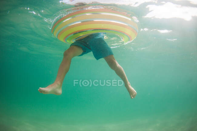 Vista submarina de un niño en un anillo de goma inflable, California, Estados Unidos - foto de stock