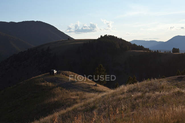 In den Bergen abgestellter Lastwagen und ein Mann, der bei Sonnenuntergang im Gras liegt, Wyoming, Vereinigte Staaten — Stockfoto