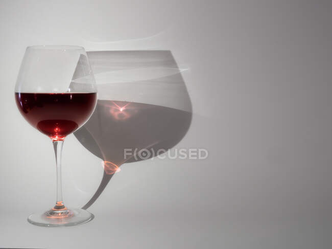 Copa de vino tinto y su sombra - foto de stock