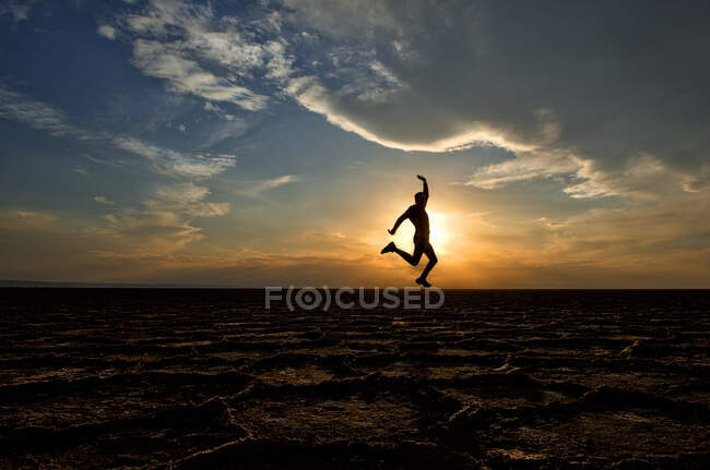 Silueta de un hombre saltando en el aire, Parque Nacional Dashte Kavir-Salt Desert, Kashan, Irán - foto de stock