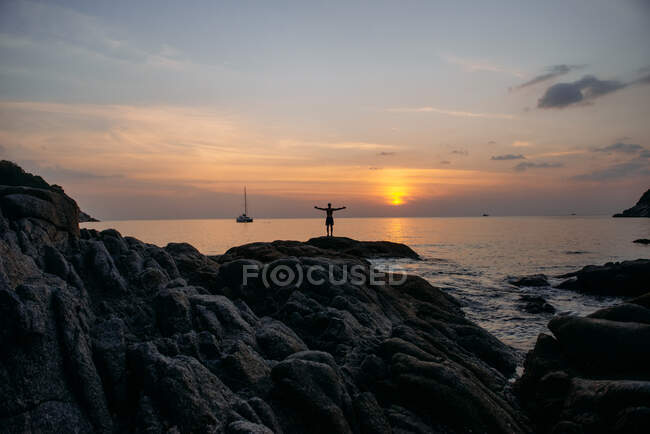 Uomo in piedi in mare con le braccia tese al tramonto, Thailandia — Foto stock