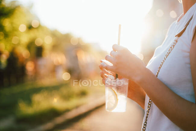Mujer de pie al aire libre con una bebida - foto de stock