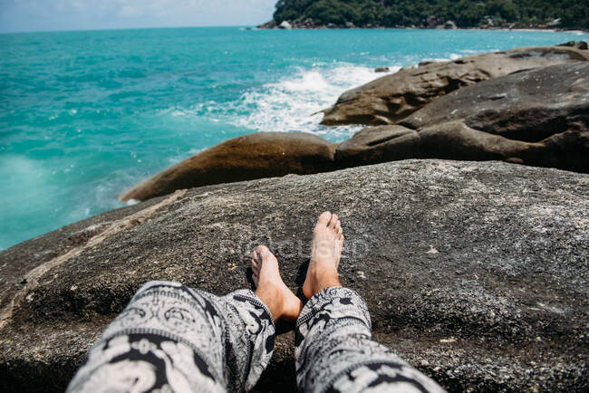 Los pies del hombre en las rocas junto al mar, Tailandia - foto de stock