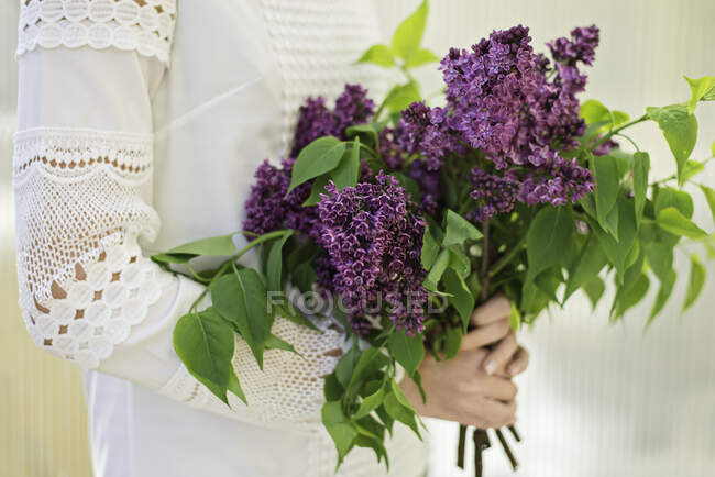 Дівчина-підліток тримає букет з бузкових квітів на весіллі — стокове фото