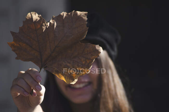Smiling teenage girl holding an autumn leaf in front of her face, Argentina — Stock Photo