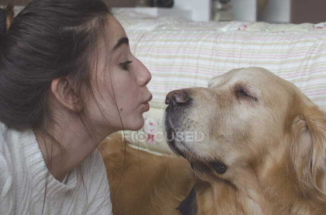 Teenage girl kissing her golden retriever dog — Stock Photo