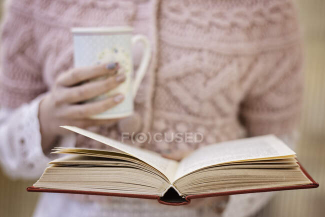 Teenage girl reading a book and drinking a cup of tea — Stock Photo